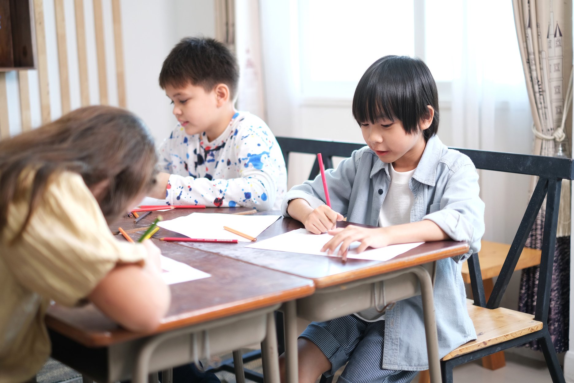 Cute primary school students are concentrating and enjoying studying.  Education, primary school, learning and people concept.